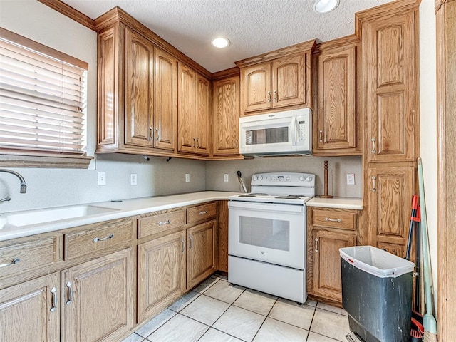 kitchen with a textured ceiling, sink, light tile patterned floors, and white appliances