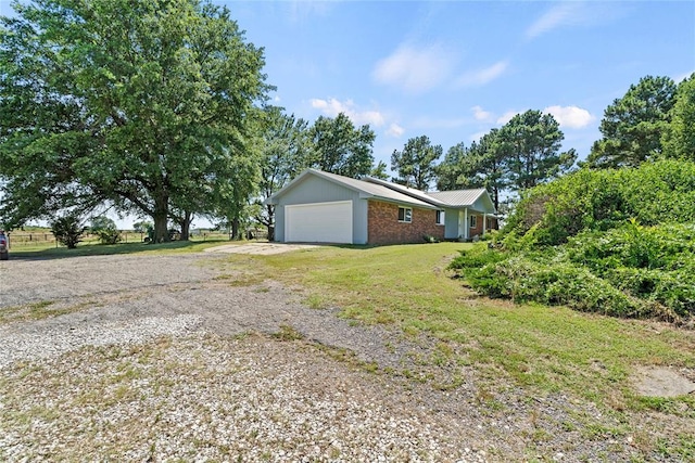 422502 E 1100th Rd, Checotah, OK 74426 - view of property exterior featuring an attached garage, driveway, brick siding, a metal roof, and a lawn