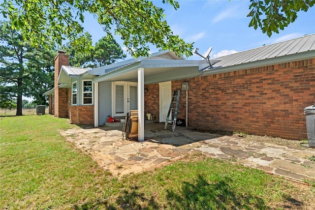 422502 E 1100th Rd, Checotah, OK 74426 - back of house with a chimney, a lawn, a metal roof, french doors, and brick siding