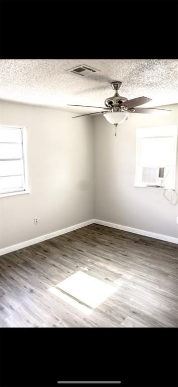 unfurnished room with hardwood / wood-style flooring, ceiling fan, cooling unit, and a textured ceiling