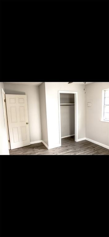 unfurnished bedroom with a closet and dark wood-type flooring