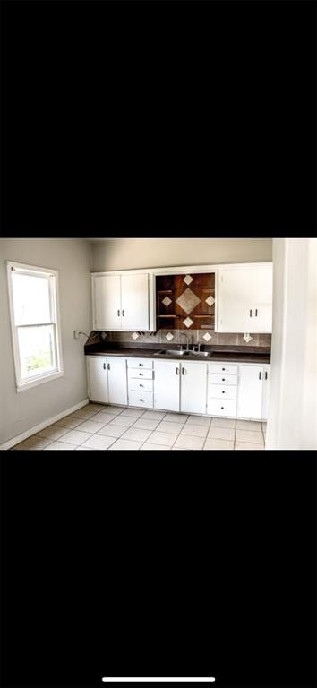 interior space with white cabinets, light tile patterned floors, and sink