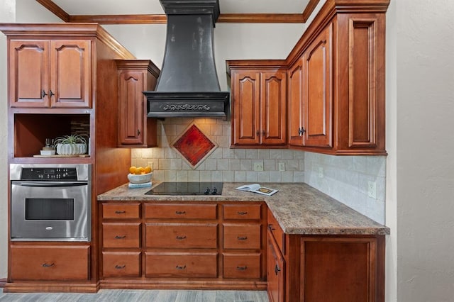 kitchen with stainless steel oven, premium range hood, black electric stovetop, decorative backsplash, and light hardwood / wood-style floors