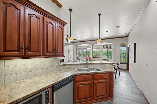 kitchen with appliances with stainless steel finishes, ceiling fan with notable chandelier, sink, decorative light fixtures, and light hardwood / wood-style floors