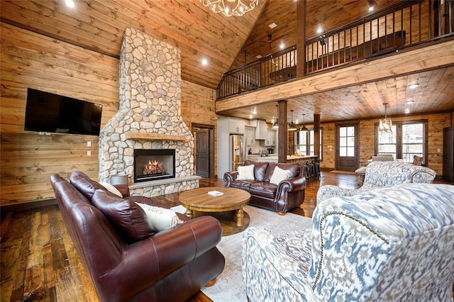 living room featuring a stone fireplace, wooden walls, high vaulted ceiling, and wood ceiling