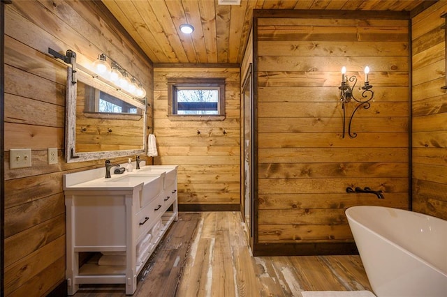 bathroom featuring vanity, wooden walls, hardwood / wood-style flooring, wooden ceiling, and a bathing tub