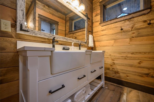 bathroom featuring hardwood / wood-style flooring, sink, and wooden walls