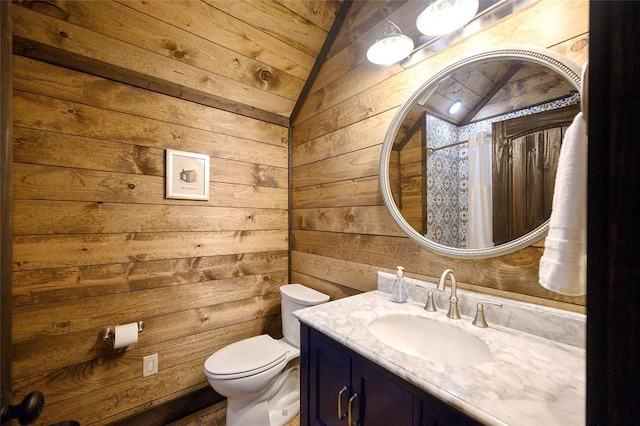 bathroom with wooden walls, vanity, vaulted ceiling, and toilet