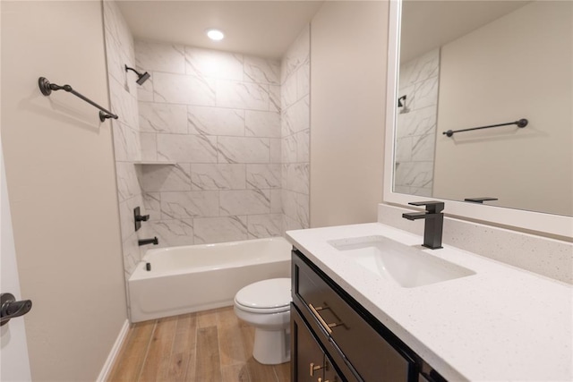 full bathroom featuring vanity, tiled shower / bath combo, hardwood / wood-style flooring, and toilet