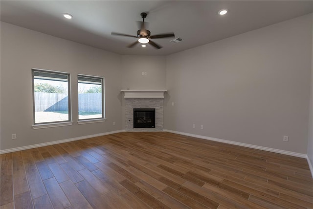 unfurnished living room featuring ceiling fan, wood-type flooring, and a fireplace