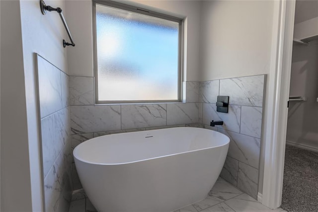 bathroom with a tub to relax in and tile walls