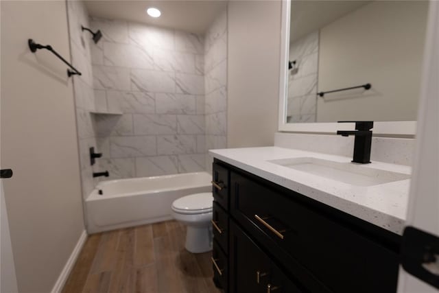 full bathroom featuring vanity, wood-type flooring, tiled shower / bath combo, and toilet