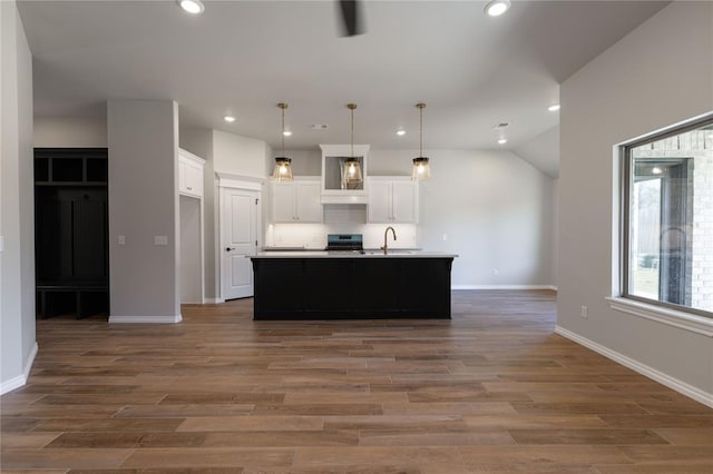 kitchen with pendant lighting, white cabinetry, dark wood-type flooring, and an island with sink