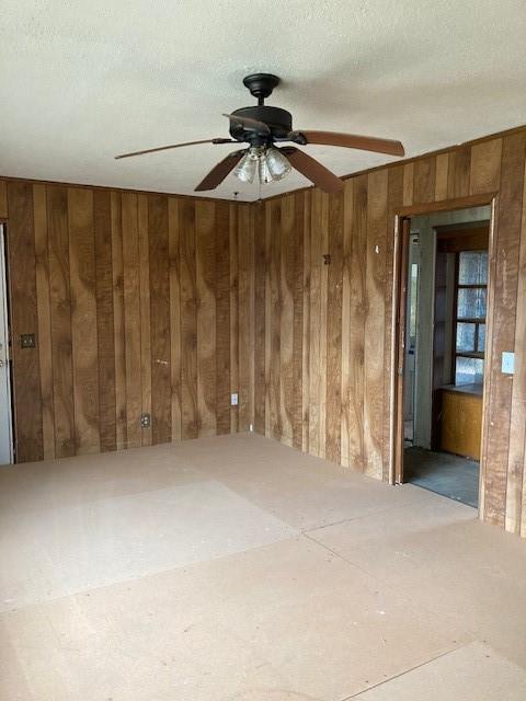 empty room with ceiling fan and a textured ceiling