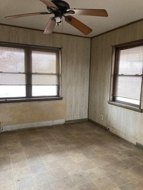 spare room with ceiling fan and wooden walls