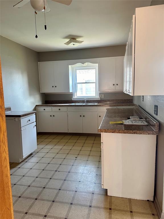 kitchen featuring ceiling fan, sink, and white cabinets