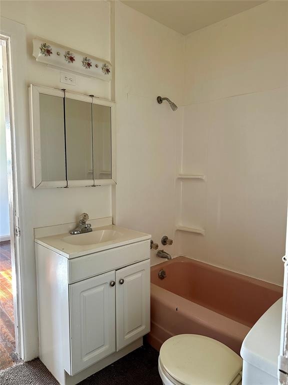 full bathroom featuring washtub / shower combination, hardwood / wood-style flooring, vanity, and toilet