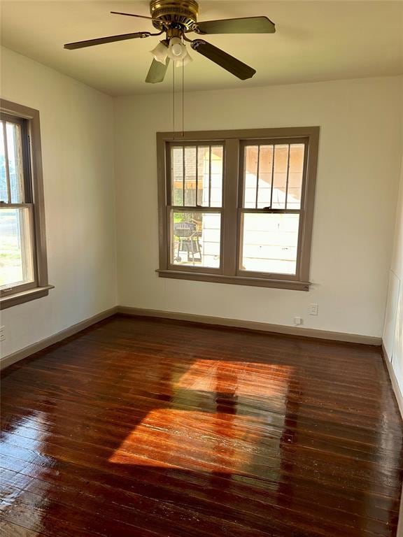 empty room with dark hardwood / wood-style flooring, plenty of natural light, and ceiling fan