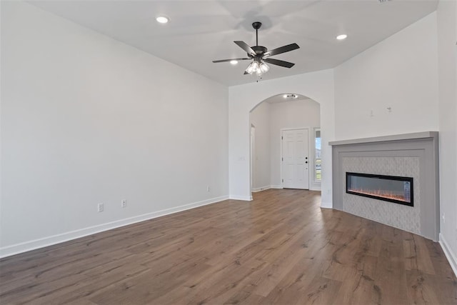 unfurnished living room with a tiled fireplace, ceiling fan, and hardwood / wood-style floors