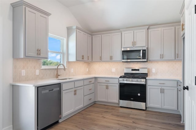 kitchen with lofted ceiling, sink, light hardwood / wood-style flooring, decorative backsplash, and stainless steel appliances