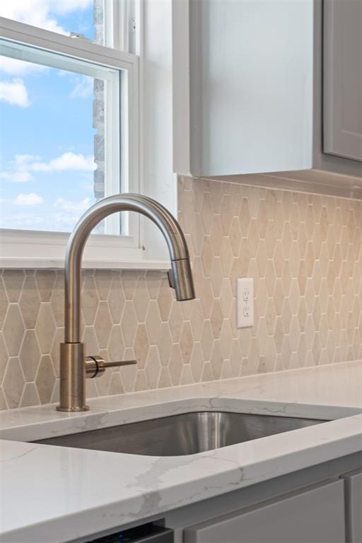 room details featuring tasteful backsplash, light stone counters, and sink