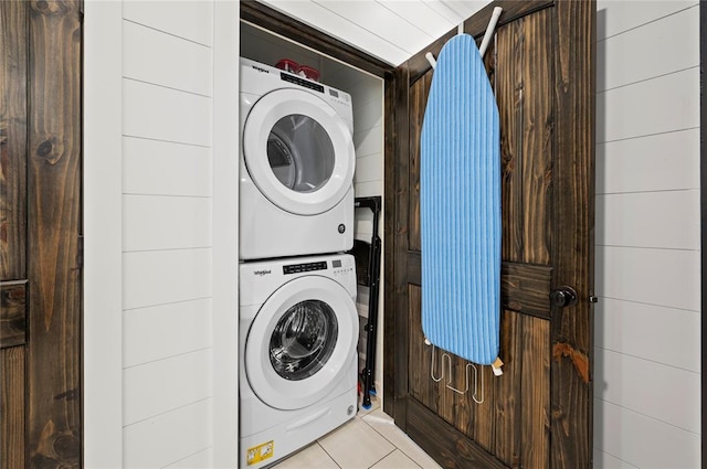 clothes washing area with stacked washer / drying machine and light tile patterned floors