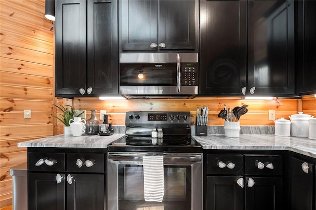 kitchen featuring stainless steel appliances, light stone counters, and wooden walls