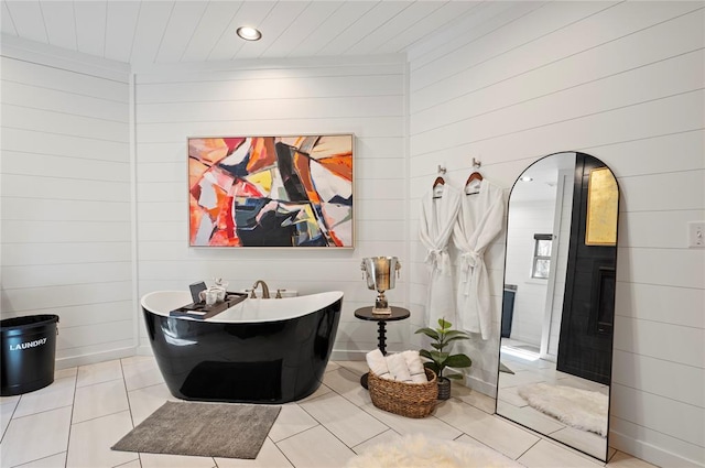 bathroom with wooden walls, tile patterned floors, and a bathing tub