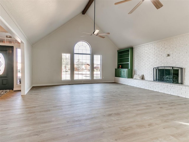 unfurnished living room featuring ceiling fan, a brick fireplace, high vaulted ceiling, beamed ceiling, and light wood-type flooring