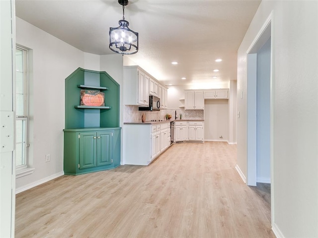 kitchen with white cabinets, light hardwood / wood-style floors, backsplash, and a chandelier