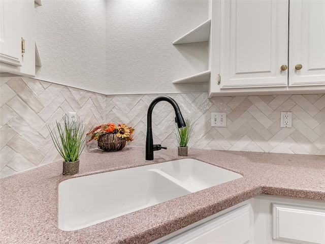 details with white cabinets, decorative backsplash, and sink