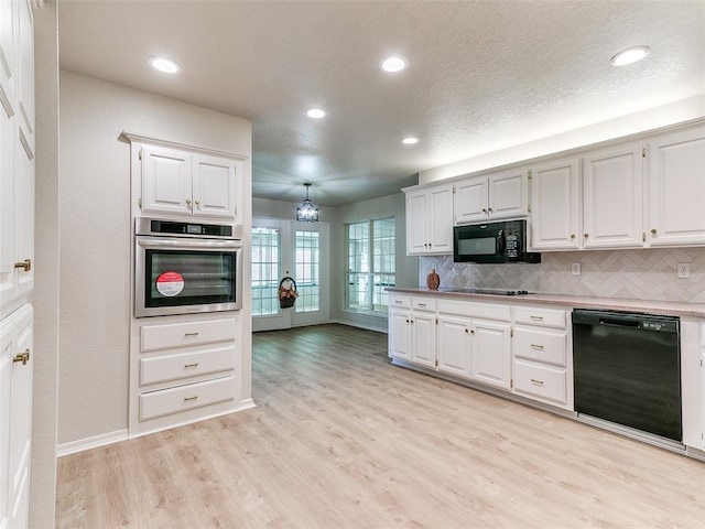 kitchen featuring white cabinets, decorative backsplash, hanging light fixtures, and black appliances