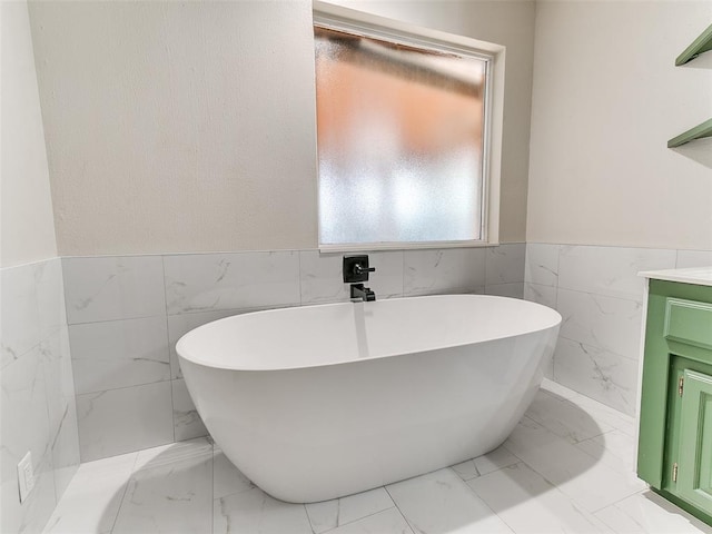 bathroom with a tub to relax in, vanity, and tile walls