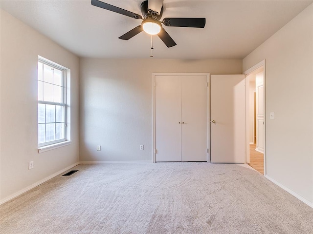 unfurnished bedroom featuring ceiling fan, a closet, and light colored carpet