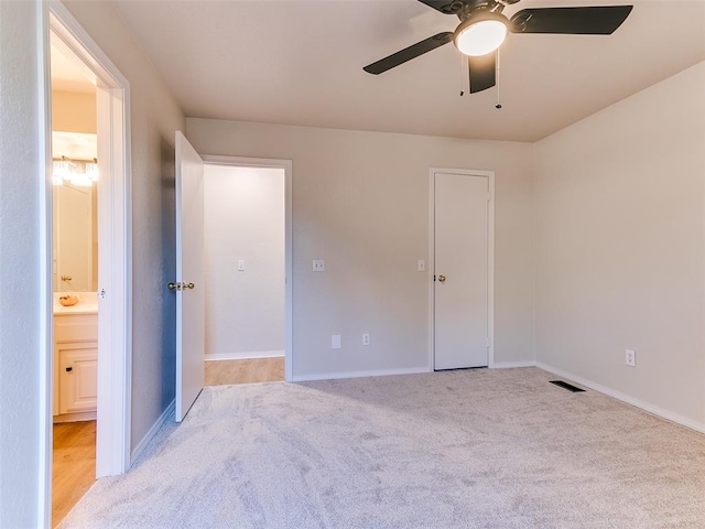 unfurnished bedroom featuring a closet, ceiling fan, ensuite bathroom, and light colored carpet