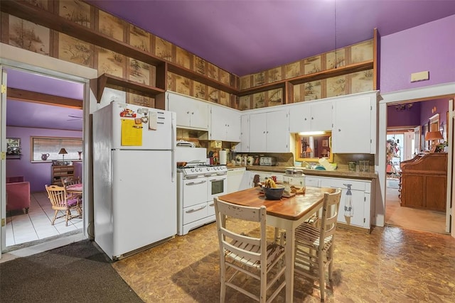 kitchen with a towering ceiling, white cabinets, and white appliances