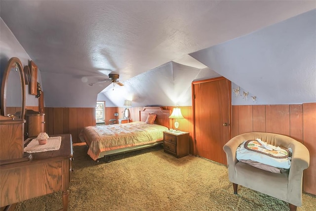 carpeted bedroom featuring ceiling fan, a textured ceiling, wooden walls, and vaulted ceiling