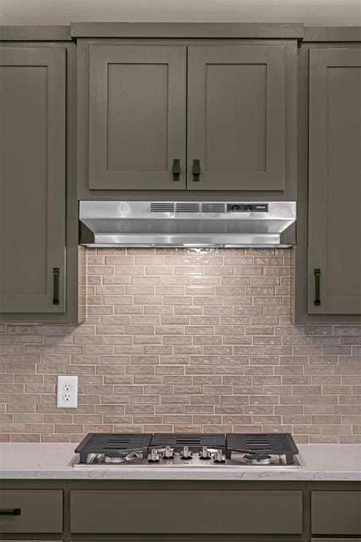 kitchen with gray cabinetry, stainless steel gas cooktop, backsplash, and extractor fan