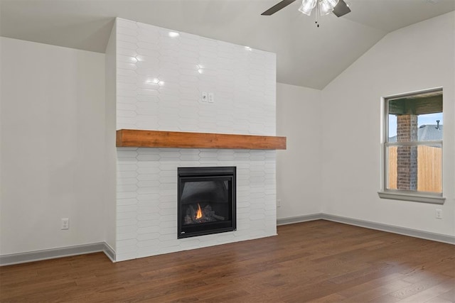 unfurnished living room featuring ceiling fan, a large fireplace, lofted ceiling, and dark wood-type flooring