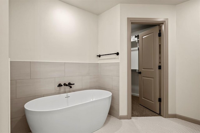 bathroom featuring tile patterned floors, a bathtub, and tile walls