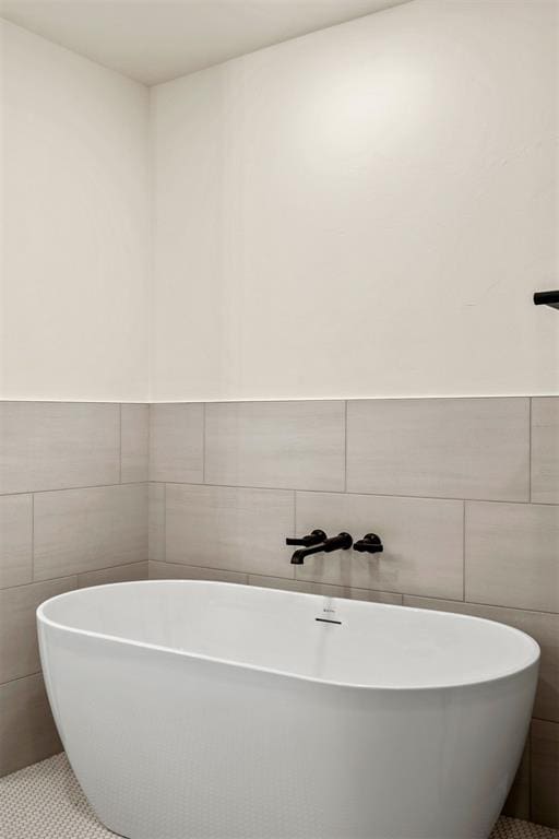 bathroom with tile patterned flooring, a bathtub, and tile walls