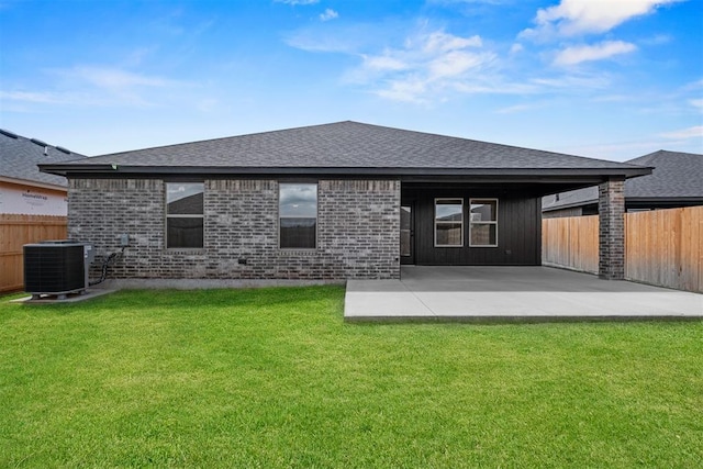 back of property with central AC unit, a patio area, and a lawn