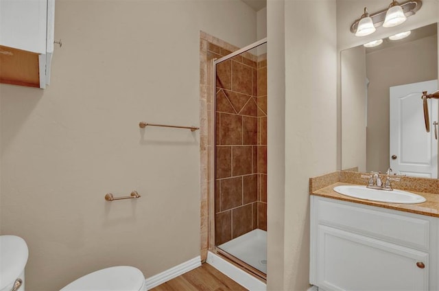 bathroom featuring hardwood / wood-style floors, vanity, a shower with door, and toilet