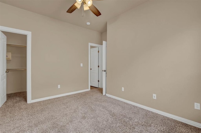 unfurnished bedroom featuring a spacious closet, a closet, ceiling fan, and light carpet