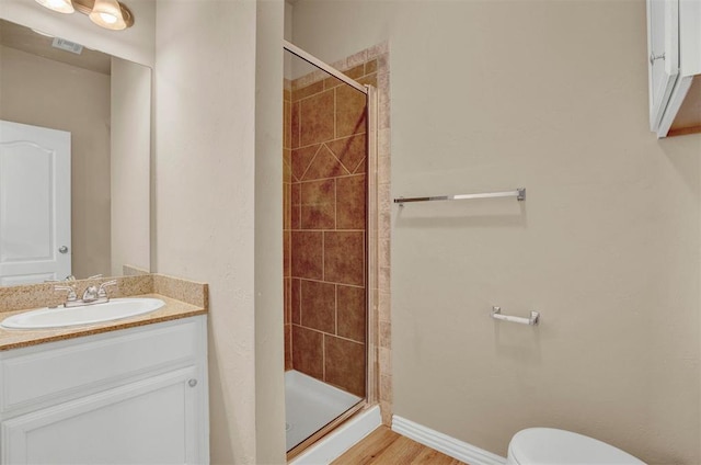 bathroom featuring hardwood / wood-style floors, vanity, toilet, and a shower with door