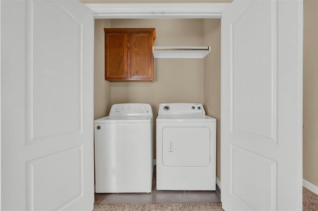 clothes washing area featuring cabinets, light tile patterned floors, and washing machine and clothes dryer