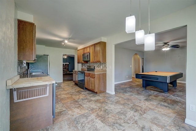 kitchen featuring ceiling fan, hanging light fixtures, stainless steel appliances, billiards, and decorative backsplash