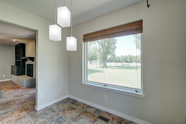 unfurnished dining area featuring a wealth of natural light and a brick fireplace