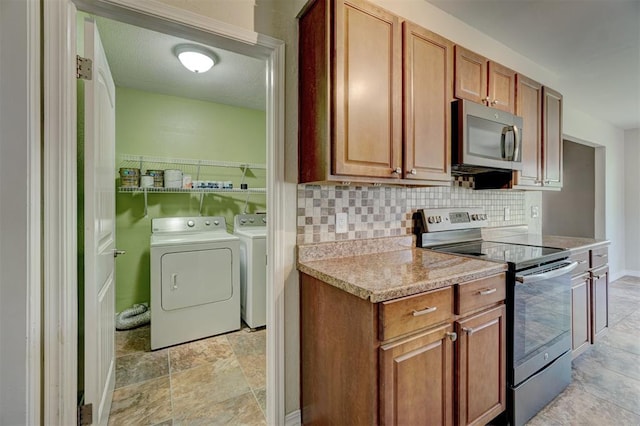 kitchen with appliances with stainless steel finishes, backsplash, light stone counters, and washing machine and clothes dryer