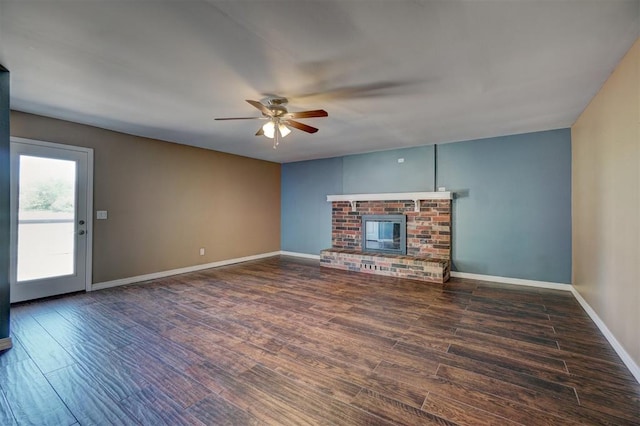 unfurnished living room with ceiling fan, dark hardwood / wood-style flooring, and a brick fireplace